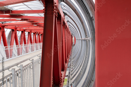 Red iron beams fastening the crosswalk. The channels are bolted, railing fencing, closed pedestrian crossing over the road.
