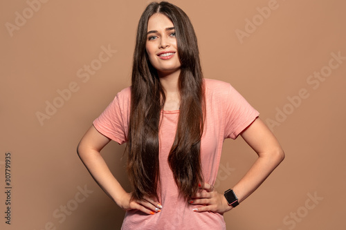 Freestyle. Young girl in t-shirt standing studio isolated on brown hands on hips posing cheerful