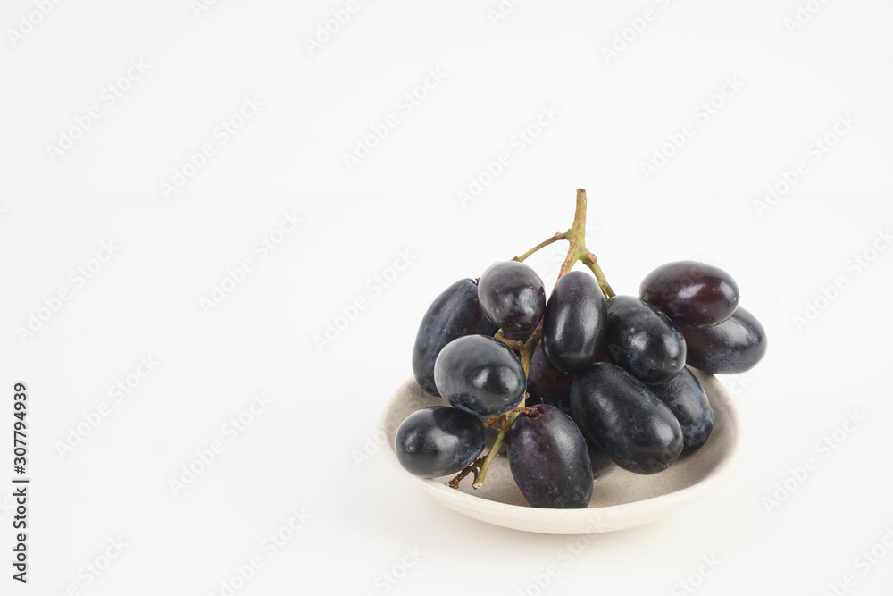 Fresh grape fruits plated over the white background Fresh grape fruits plated over the white background