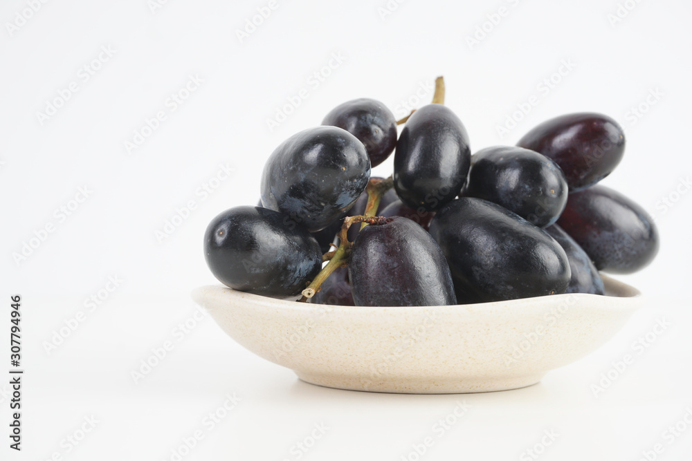 Fresh grape fruits plated over the white background Fresh grape fruits plated over the white background