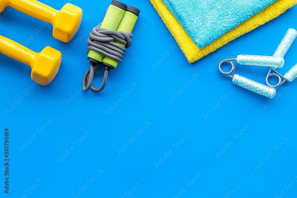 Gym equipment - dumbbells, jump rope - frame on blue background top-down copy space Gym equipment - dumbbells, jump rope - frame on blue background top-down copy space