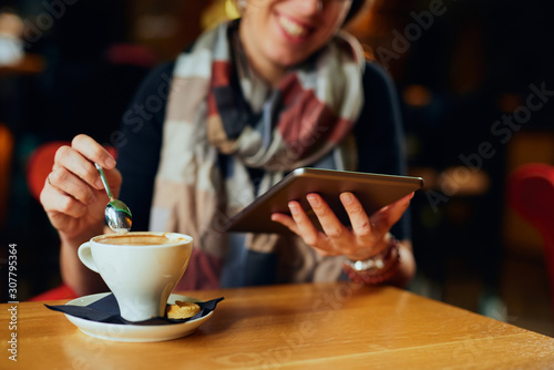 Beautiful Caucasian woman with coffee looking at her tablet 