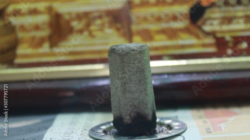 Close up shot of dhoop batti / incense stick burning with some smoke on the pooja room and some light passing through the dhoop batti photo