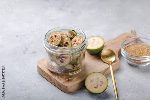 Ground green feijoa with sugar on a wooden cutting Board in a glass jar. Gray background. Top view. Healthy eating ingredients concept