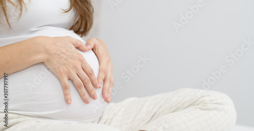 young beautiful pregnant woman hugging her belly on the bed in the bedroom