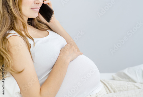 Pregnant woman looking at her mobile at home