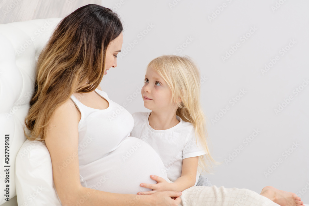 Cute little girl is hugging her beautiful pregnant mom Cute little girl is hugging her beautiful pregnant mom