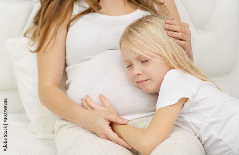 Cute little girl is hugging her beautiful pregnant mom Cute little girl is hugging her beautiful pregnant mom