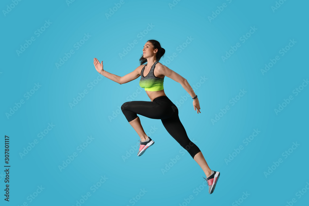 Athletic young woman running on light blue background, side view