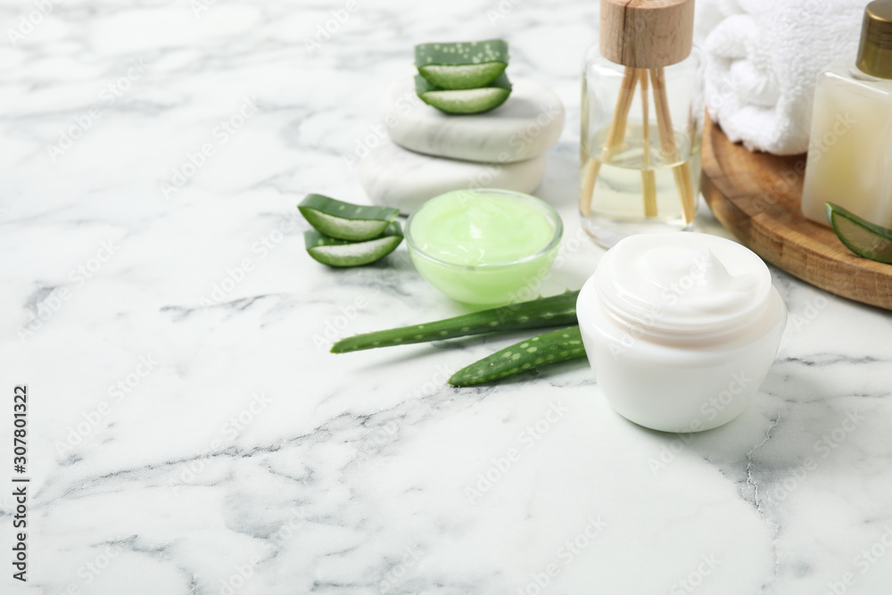 Different cosmetic products and aloe on white marble table, space for text Different cosmetic products and aloe on white marble table, space for text