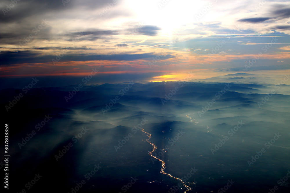 spectacular sunset seen from an airplane with the sun reflecting off a river and the mountains in the background spectacular sunset seen from an airplane with the sun reflecting off a river and the mountains in the background