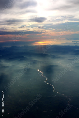spectacular sunset seen from an airplane with the sun reflecting off a river and the mountains in the background