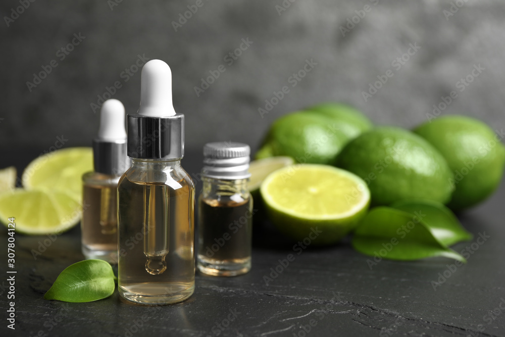 Lime essential oil and cut citrus fruits on black table Lime essential oil and cut citrus fruits on black table