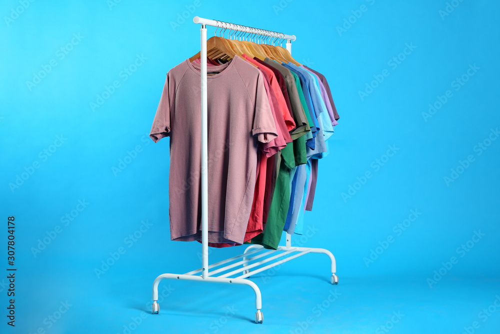 Obraz premium Colorful clothes hanging on rack against light blue background