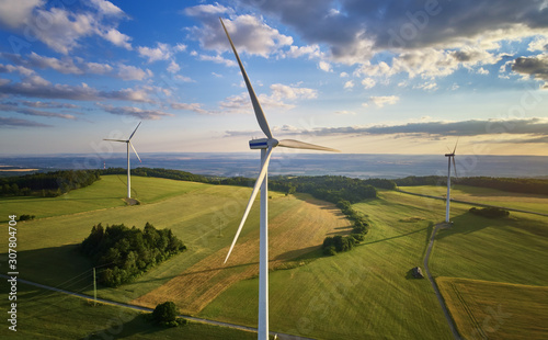 Aerial view of wind turbine farm. Wind power plants in green landscape against sunset sky with clouds. Aerial, drone inspection of wind turbine. photo