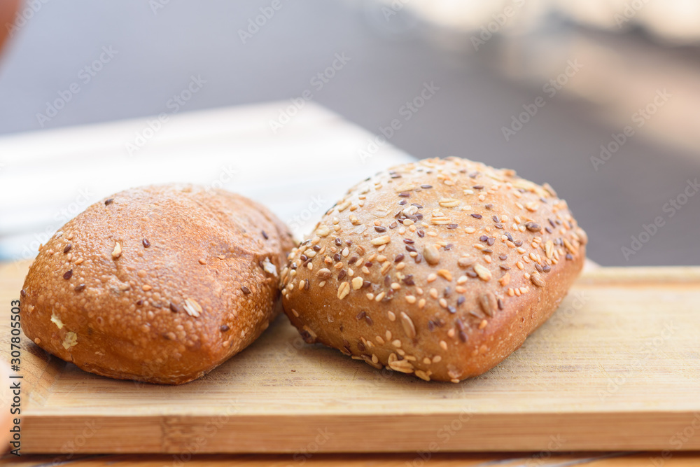 Buns with seeds and grain. Fresh rustic crusty bread on wooden board.