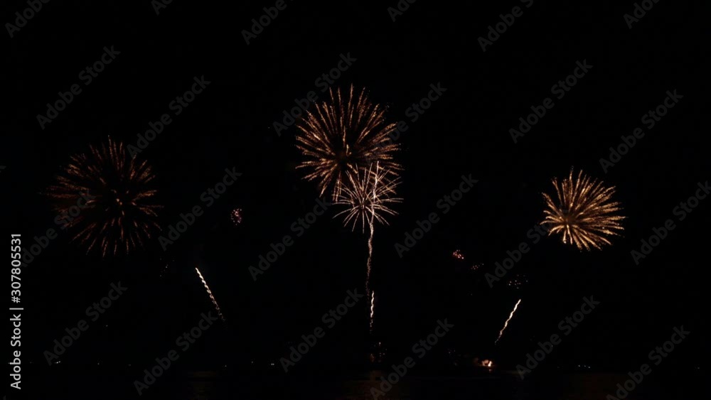 Golden big shiny fireworks with bokeh lights in the night sky. Glowing firework show. New Year's Eve fireworks celebration. Fireworks Festival. Golden big shiny fireworks with bokeh lights in the night sky. Glowing firework show. New Year's Eve fireworks celebration. Fireworks Festival.