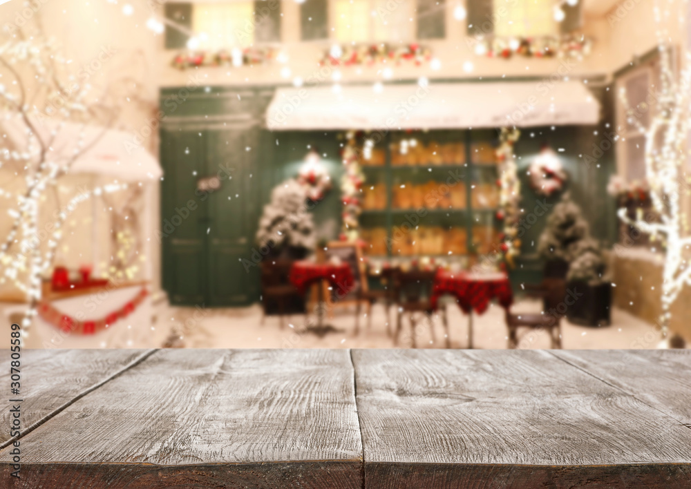 Empty wooden surface and blurred view of outdoor cafe in winter. Christmas holiday