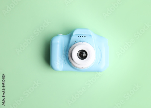 Light blue toy camera on light green background, top view. Future photographer