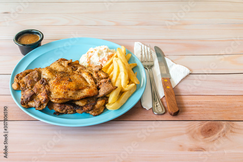 Double chicken chop with coleslaw and french fries on blue plate. Western food with cutleries on table concept.