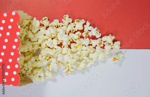 top view of spread popcorn with red dotted popcorn box on white and red background