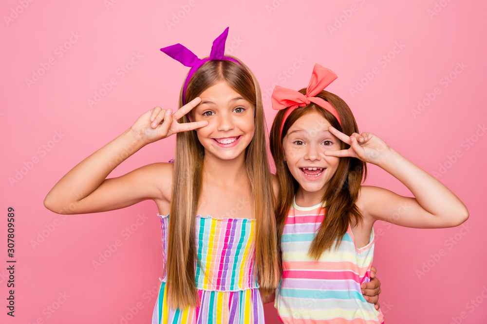Portrait of lovely children hugging making v-signs wearing bright dress skirt isolated over pink background Portrait of lovely children hugging making v-signs wearing bright dress skirt isolated over pink background
