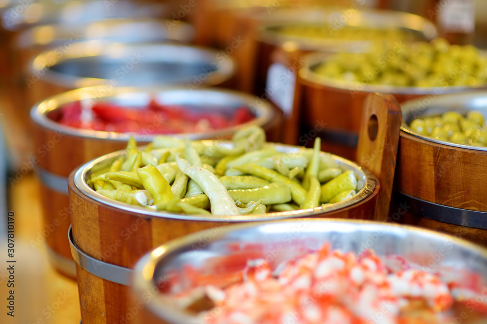 Fototapeta premium Assorted organic pickled olives, garlic, hot peppers, capers and sundried tomatos sold on a marketplace in Vilnius, Lithuania.