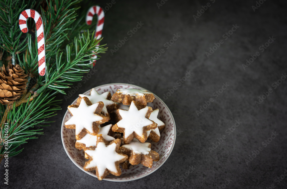 A cup with christmas biscuits and fir branch on a black table and copy space, top view A cup with christmas biscuits and fir branch on a black table and copy space, top view