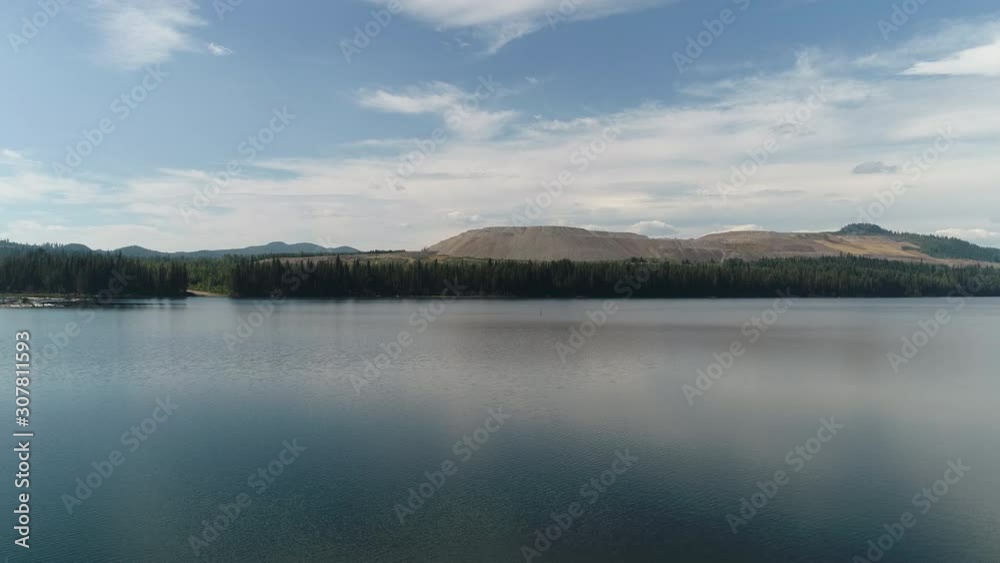 Drone, aerial, slowly panning, wide shot of a beautiful lake with trees and mountains. Drone, aerial, slowly panning, wide shot of a beautiful lake with trees and mountains.