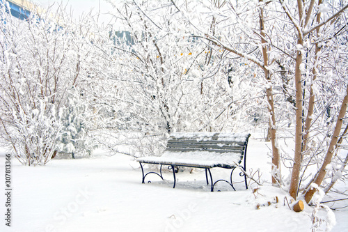 Snow covered bench in a deserted park. Winter. Russia