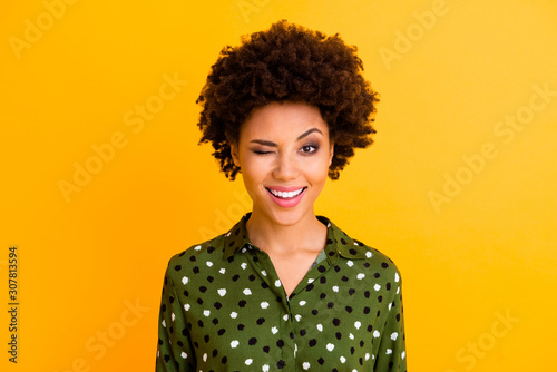 Photo of beautiful pretty dark skin wavy lady toothy beaming smiling winking eye flirty girlish mood wear green dotted shirt blouse isolated yellow color background
