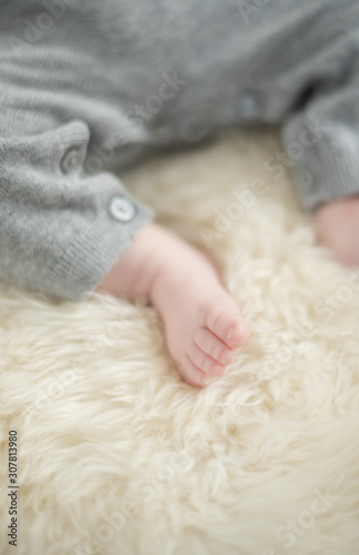 A beautiful soft delicate warm young baby foot photographed with a shallow depth of field. gentle calm colours and feel. baby care and well being. babies feet on a cream fur rug. © dannyburn