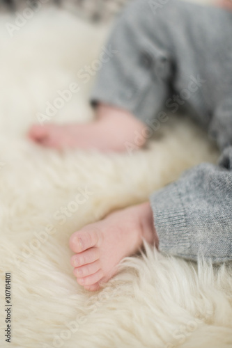 A beautiful soft delicate warm young baby foot photographed with a shallow depth of field. gentle calm colours and feel. baby care and well being. babies feet on a cream fur rug.