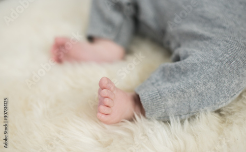 A beautiful soft delicate warm young baby foot photographed with a shallow depth of field. gentle calm colours and feel. baby care and well being. babies feet on a cream fur rug.