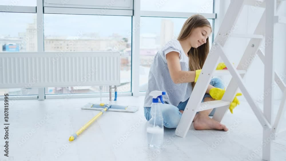 Smiling girl wiping furniture at home