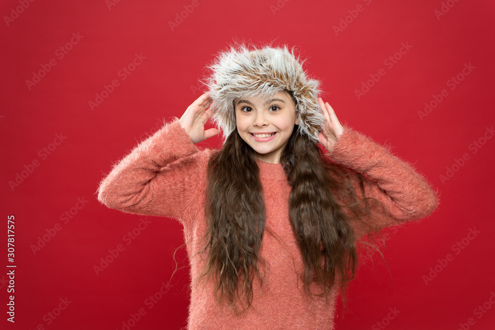 Little cute girl in winter style red wall. holiday activity outdoor. small child ready for winter. seasonal health care. kid fashion. Warm clothes and accessory tips. happy little girl in earflap hat Little cute girl in winter style red wall. holiday activity outdoor. small child ready for winter. seasonal health care. kid fashion. Warm clothes and accessory tips. happy little girl in earflap hat