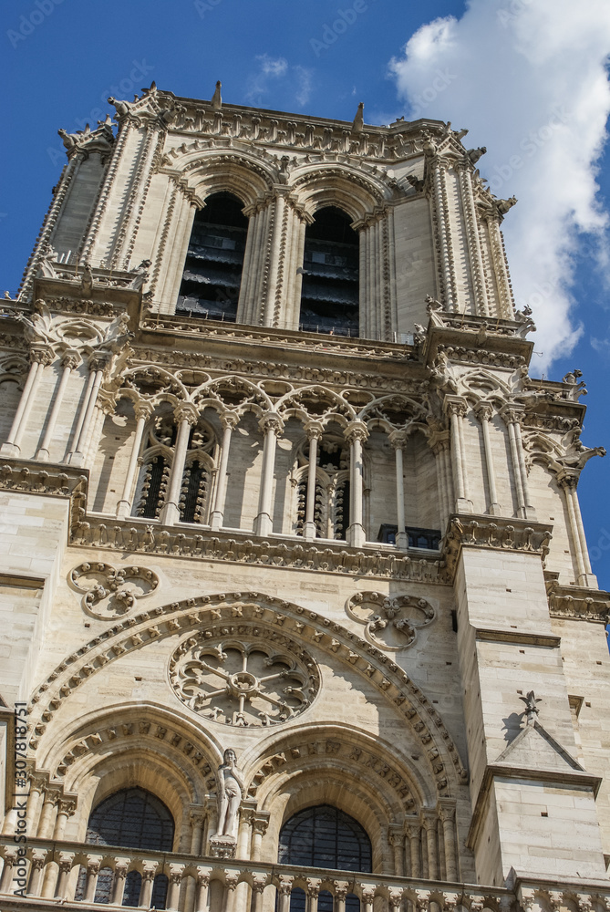 Close up of one of the towers of the Notre dame in Paris on a summer day with some clouds, France