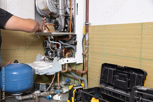 Obraz na płótnie plumber fixing central heating system, Worker servicing a gas boiler w salonie
