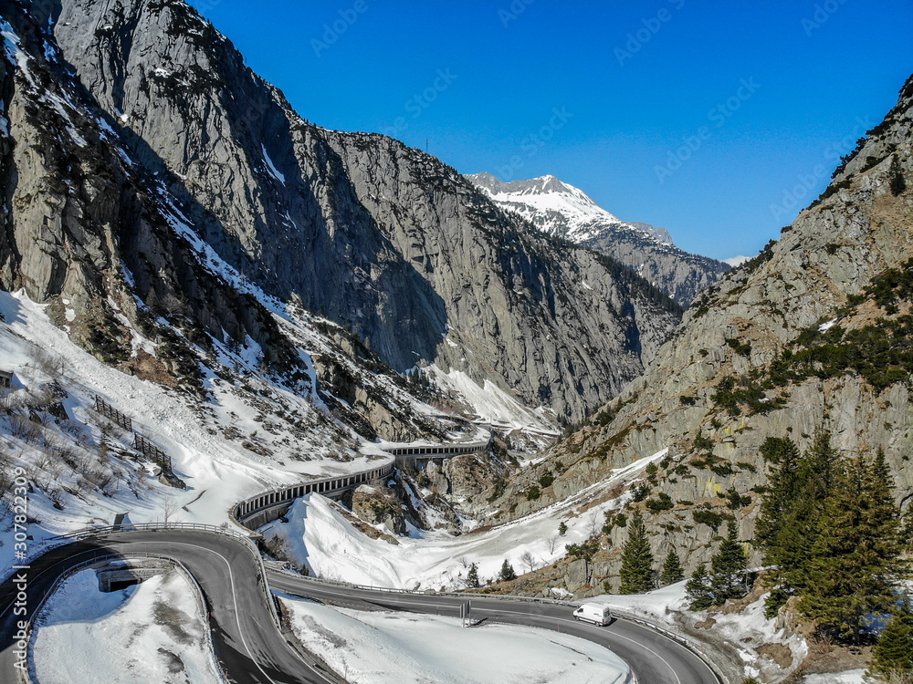 scenic view of mountain road in front of snowcapped mountains against clear sky