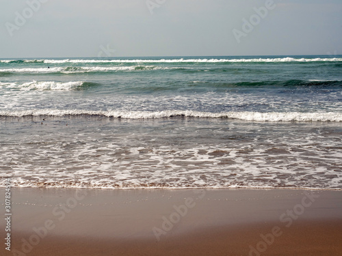 Ocean wave and wet sand on a beach, abstract nature background.