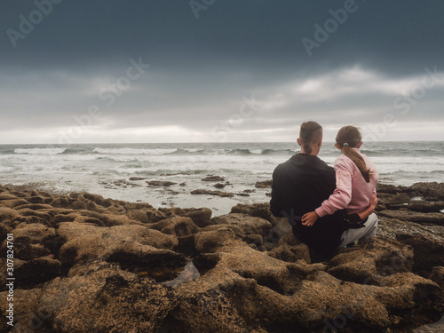 Brother and sister watching oceans wave. Dramatic stormy sky. Atlantic ocean, Burren, Ireland.