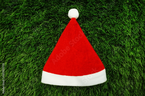 Red Christmas hat with space copy on green artificial grass background