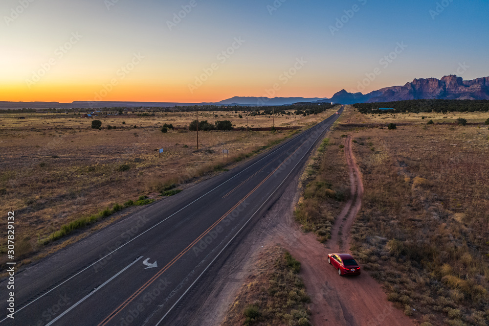 Top view of highway and red car on the road, close to Colorado city. Cottonwood point. Sunset sky, mountains. Arizona, USA