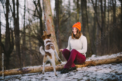 Fototapeta Naklejka Na Ścianę i Meble -  Young woman playing with her fox terrier in the forest. Best friend concept.