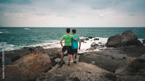 two men standing on Rock looking at ocean