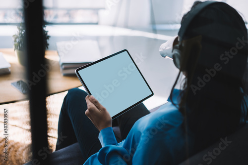 Faceless female surfing tablet while drinking coffee at modern home