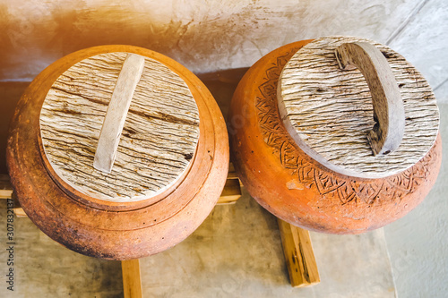 Obraz na plátne Row of earthen jars with wood lids and rough gray floor for water storage in Asian house