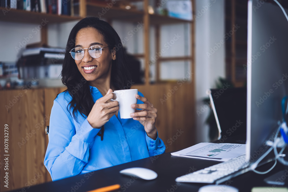 Black businesswoman sitting in office with cup