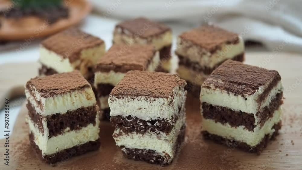 The chef sprinkles tiramisu cake with cocoa powder. Decoration of chocolate dessert.