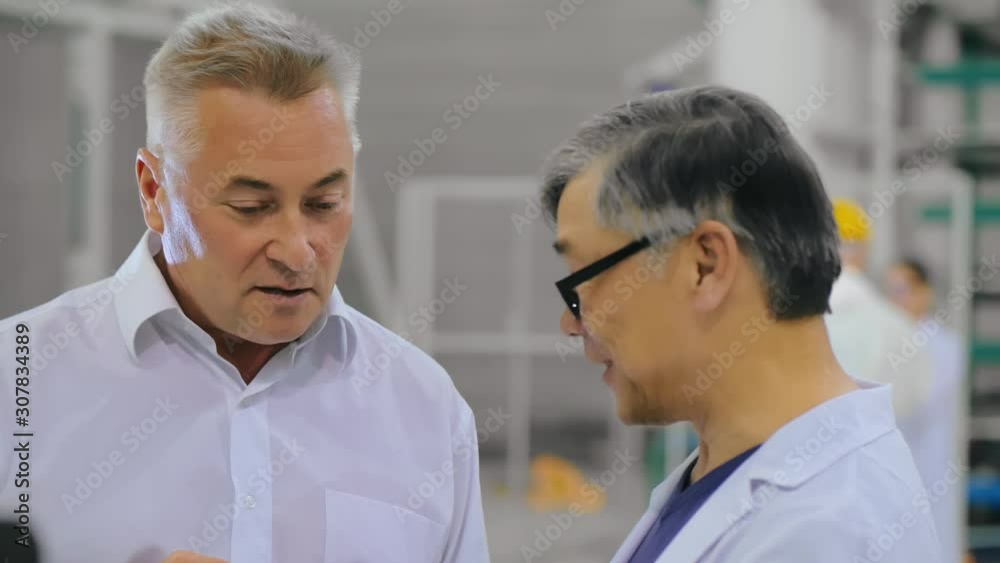 Two colleagues engineers or scientists talk discuss in research laboratory of industrial factory. White collars communicate in scientific center